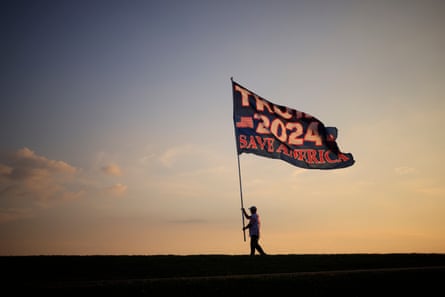 A man waves an enormous Trump 2024 flag.
