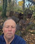 A selfie showing a man with discarded industrial drums behind him