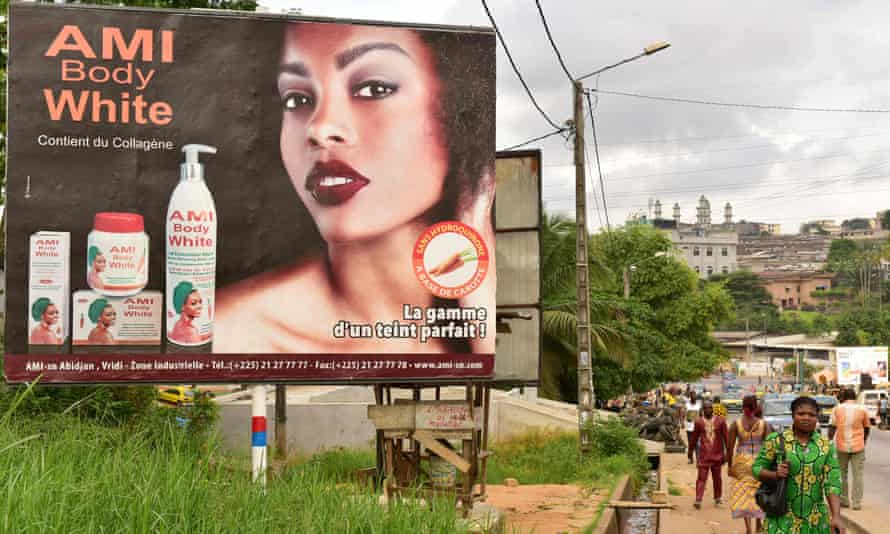 Colorism is not just an American phenomenon.. Pedestrians walk past a hoarding advertising a skin-whitening cream in Abidjan, Ivory Coast.