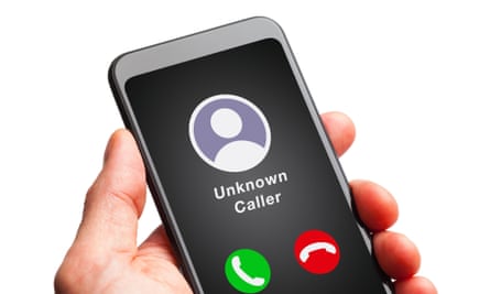 A hand holds up a smartphone with the words saying ‘unknown caller’