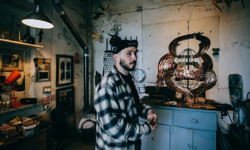 Vasya Dmytryk in his studio, with a metal birdcage-like sculpture on a cabinet behind him
