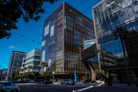 OpenAI's San Francisco headquarters, a glass tower with a bronze grid facade, rises above the street