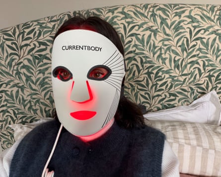 A person wears a CurrentBody LED face mask with glowing red light over their face
