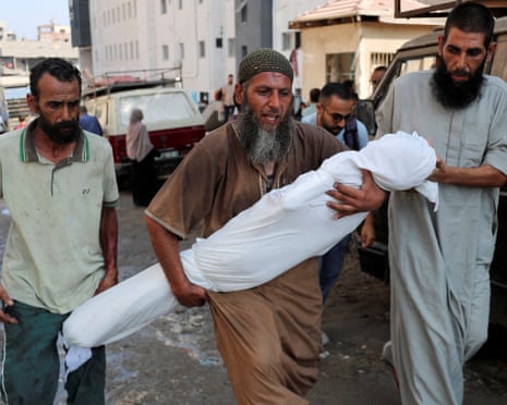 A mourner carries the body of a Palestinian, who according to the medics, was killed in overnight Israeli strikes, outside Al-Shifa hospital in Gaza, July 23, 2025.