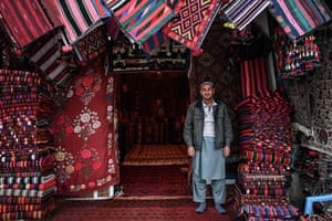 A vendor selling carpets stands outside his shop in Mazar-i-Sharif