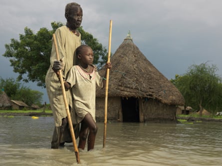 David Deng, who is blind, navigates his way through the floods with the help of his nine-year-old granddaughter, Angelina Nyagok.