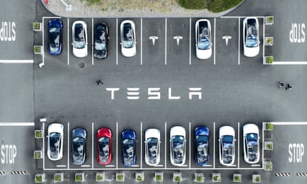 An aerial view of Tesla cars in a branded factory lot
