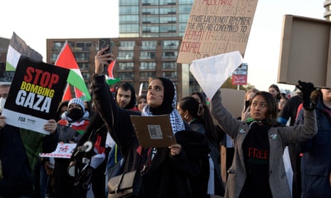 “Stop boming Gaza” reads the sign as people march through London