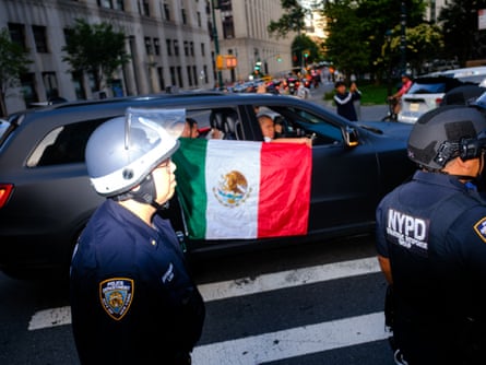 People hold a Mexican flag out the window of a car towards police officers