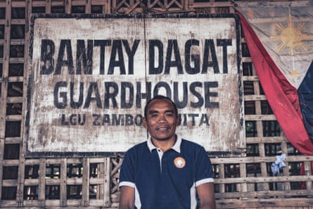 Antonio ‘Toni’ Yocor standing against a wooden sign for the Bantay Dagat guardhouse