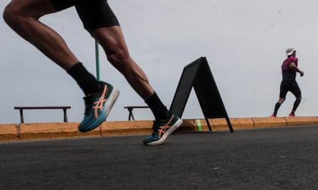 Image shows legs of a runner taking off on a road race while another runner can be seen in the background