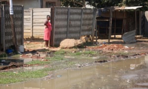 A resident watches raw sewage flow just outside her house in Glen View.