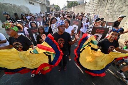 People in the street, some with flowing yellow skirts trimmed in red, green and black