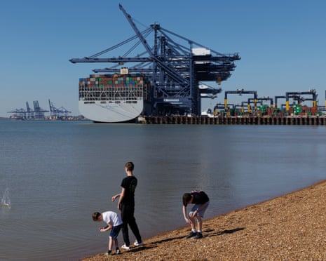 Kids throw pebbles into the as container ships load and unload in the background