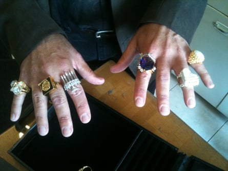 His hands, with an assortment of huge and gaudy rings