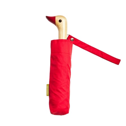 Original Duckhead umbrella in tomato red is folded into its umbrella case with the duckhead handle facing to the left.