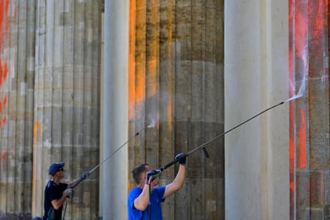 Two men remove paint from the columns of Berlin’s landmark Brandenburg Gate on 17 September 2023.