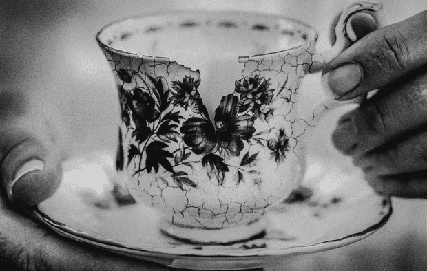 Close up of person's hands holding cup and saucer