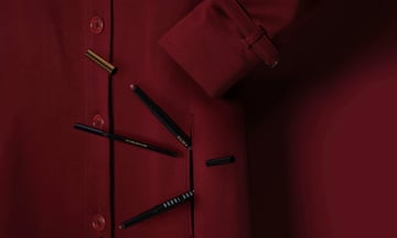 Three burgundy and brown toned makeup pencils, with a burgundy raincoat as the backdrop.