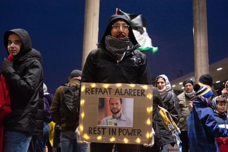 a man holding a photo of a man at a nighttime protest