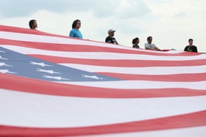 people stand near a giant US flag