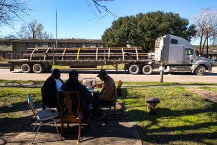 Men play dominoes in a lot with a big rig parked nearby.