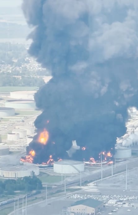 Aerial view of enormous facility fire with thick black smoke.