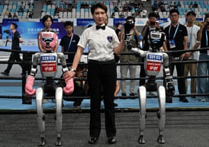 The referee holds up the arm of the winning robot