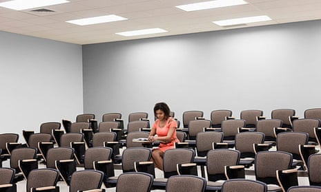 A university student sits alone in an empty lecture hall.