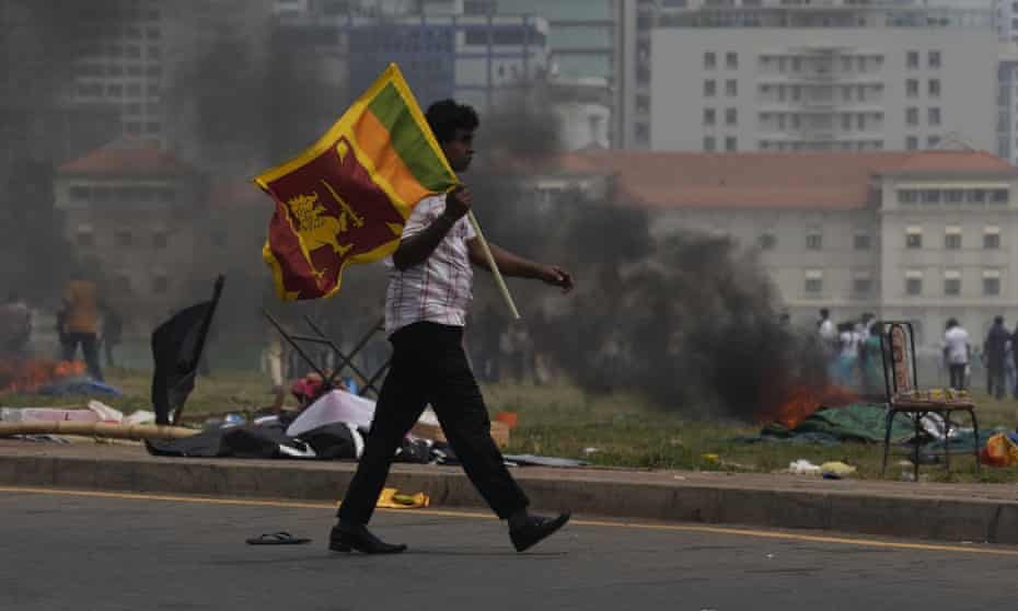 Un partidario del gobierno de Mahinda Rajapaksa, que dimitió esta semana tras semanas de disturbios, lleva la bandera de Sri Lanka por Colombo.