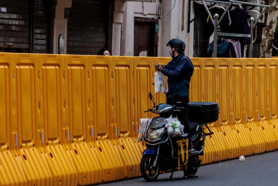 Un homme livre de la nourriture aux personnes dans l'enceinte en quarantaine du côté Puxi de Shanghai.