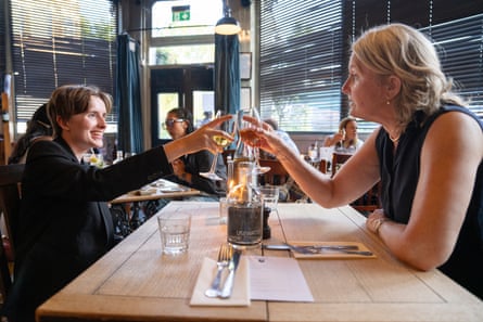 Margaret and Clare clink wine glasses across a restaurant table