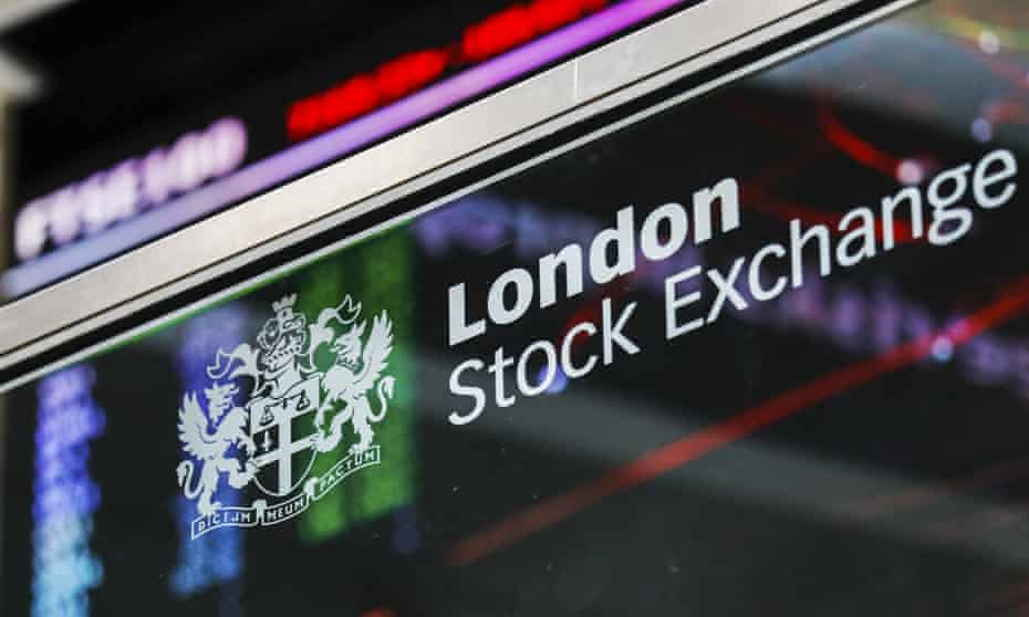London Stock Exchange logo in front of FTSE 100 Index share price information in the atrium of the LSE