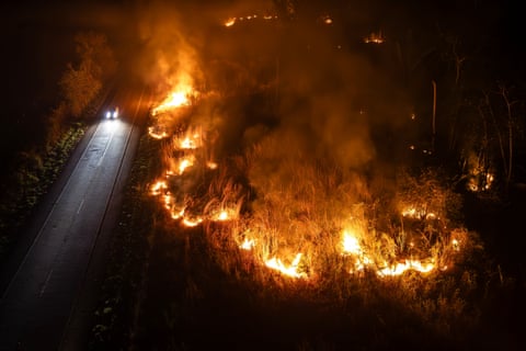 Um carro dirigindo ao lado de um incêndio florestal