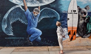 A woman looks at a mural of a health worker with wings holding a globe on International Nurses Day in Melbourne on 12 May 2020.