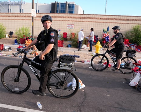 Police officers ride bicycles outside State Farm stadium as crowds arrive.