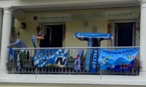 Vincenzo La Porta is pictured on a balcony wearing a blue baseball cap and holding a scarf.