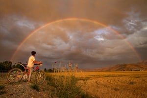 Edremit, Turkey. A boy looks at a rainbow that appeared over a field after a rain shower
