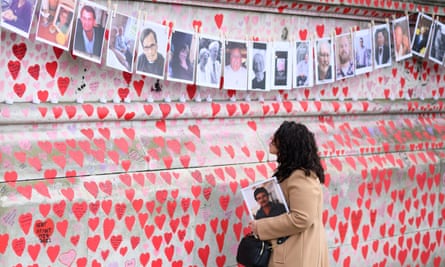 Members of the public view the photos of some of those who died during the Covid-19 pandemic, on the first anniversary of the creation of the Covid Memorial Wall in London.