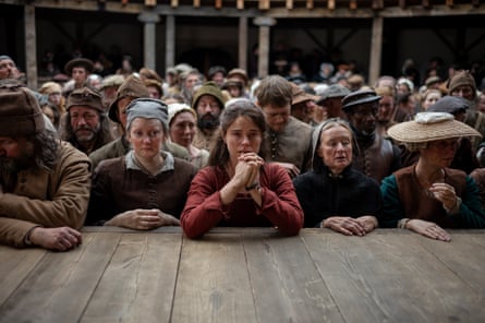 Buckley standing in front of a stage surrounded by other actors all in period costume