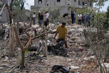 A man removes a damaged scooter from the debris of a destroyed house.