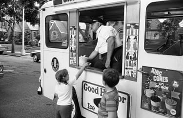Two children stand next to an ice-cream truck
