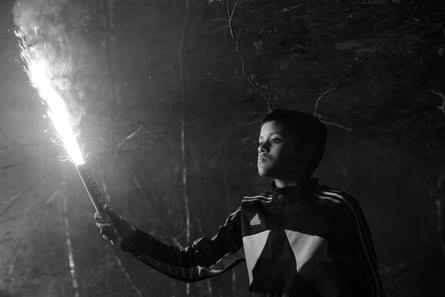 A black and white image of a young boy holding a lit roman candle