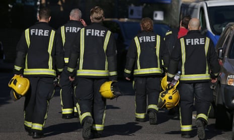 Members of the fire brigade walk near Grenfell Tower