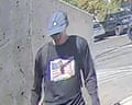 A person wearing a baseball cap, jeans and a black T-shirt with a flag of America on it.