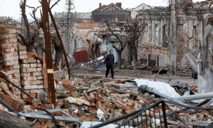 A man walks past damaged buildings in Mariupol.