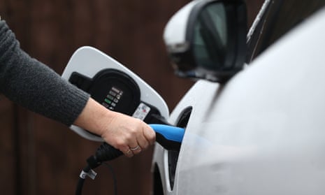 An electric charging cable connected to a Jaguar I-Pace electric car at a residential home