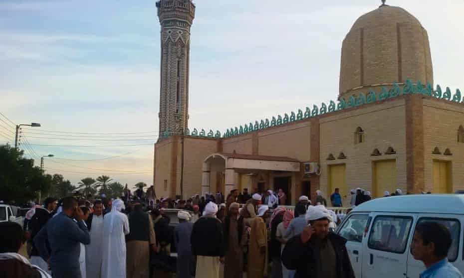 People gather at the site of the Sinai mosque where a bomb and gun assault left at least 235 people dead and scores more injured.