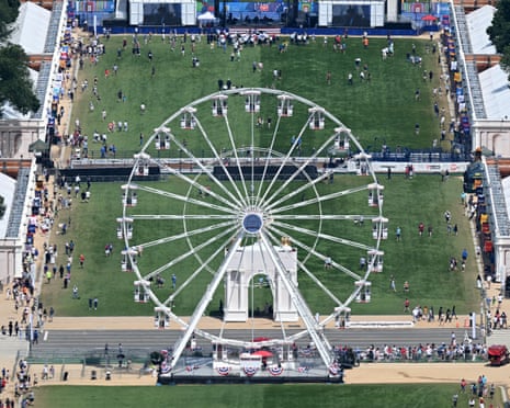 Aerial view of a large white Ferris wheel on the National Mall with crowds and structures around it