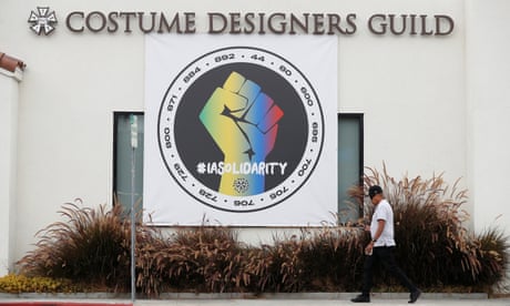 A person walks by a banner hung in support of the the International Alliance of Theatrical Stage Employees (IATSE) outside the Costume Designers Guild offices in Burbank, California, U.S., October 7, 2021. REUTERS/Mario Anzuoni